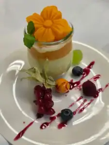 Gedämpfter Kürbis in einem Glas mit Kokoscreme und angerichtet mit Früchten und Beeren